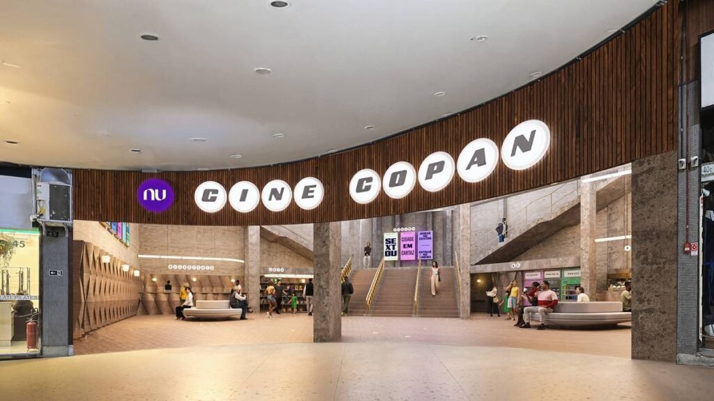 Fachada do Nu Cine Copan, um cinema icônico de São Paulo, com iluminação ambiente e movimento de pessoas na frente.