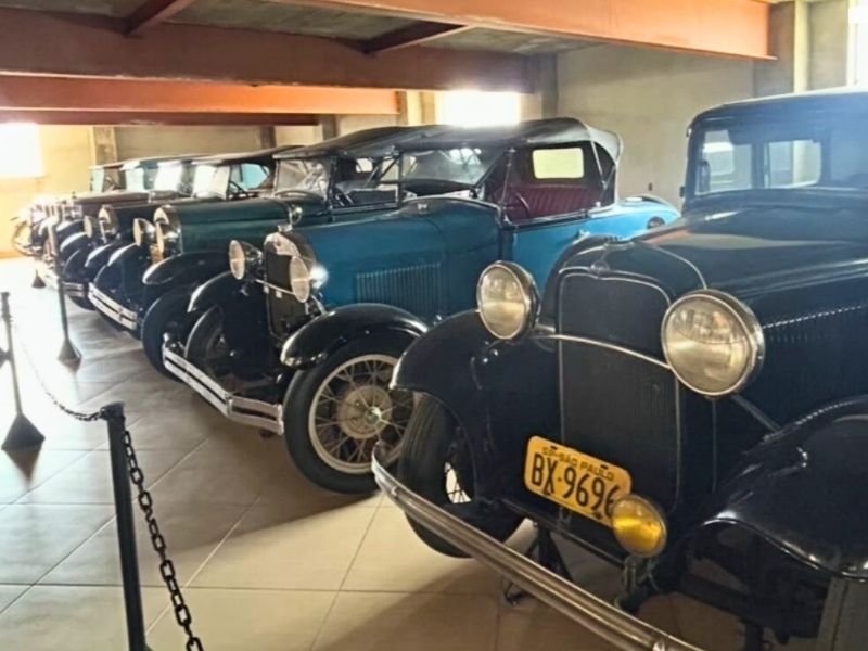 Visita ao Museu Mairiporã com crianças explorando automóveis clássicos e peças ferroviárias.
