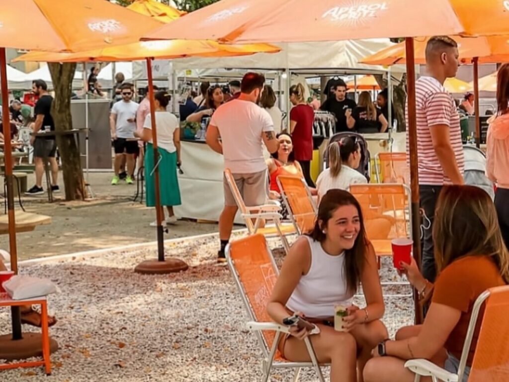 Visitantes desfrutando do festival gastronômico Brooklin Taste em um ambiente ao ar livre inspirado no Central Park de Nova York, com bistrôs e food trucks.